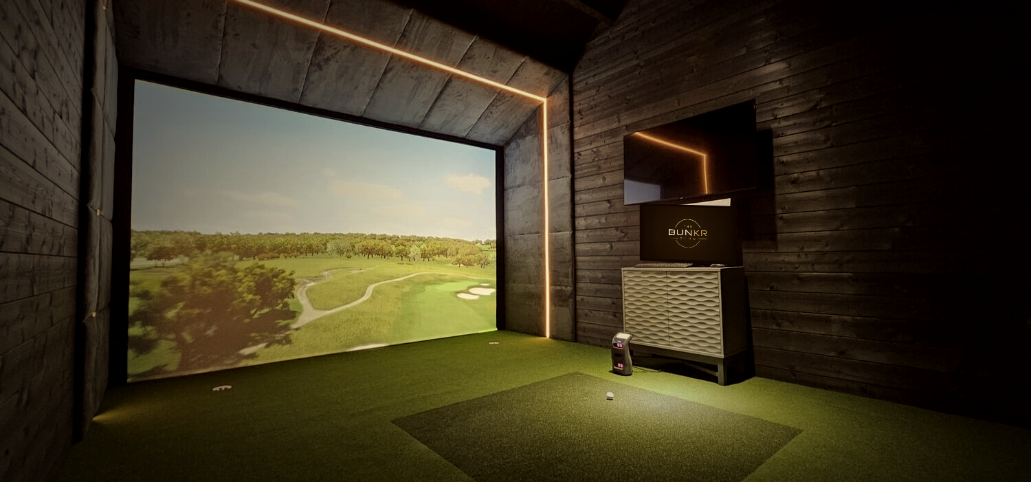 A player mid-swing in a Trackman simulator bay